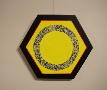 Obraz abstrakcyjny o kształcie sześciokąta w kolorze jaskrawożółtym, obramowany czarną i czerwona liną. W środek wpisany okrąg.