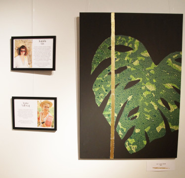 Na fotografii fragment ekspozycji - biogramy artystek oraz jeden z obrazów (na czarnym tle zielony liść).