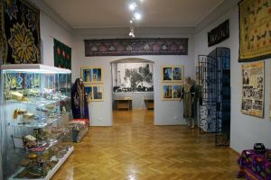 Fragment ekspozycji - ogólny widok na sale (widoczne gabloty m.in. z biżuterią i ceramiką, na ścianach barwne tkaniny oraz...