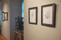 Prace artystki wiszące na ścianie, przedstawiające połączenie architektury i  zwierząt