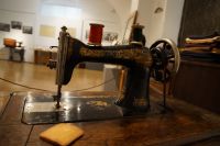 Co nieco o szyciu - fragment ekspozycji - na pierwszym planie stara maszyna do szycia, krawieckie mydełko, tło rozmyte