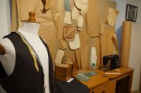 Fragment ekspozycji - na pierwszym planie manekin krawiecki z metrem i w kamizelce, w tle maszyna do szycia