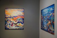 Fragment ekspozycji - widoczne dwa obrazy, w żywych kolorach, pełne dynamicznych linii, piramid, zygzaków