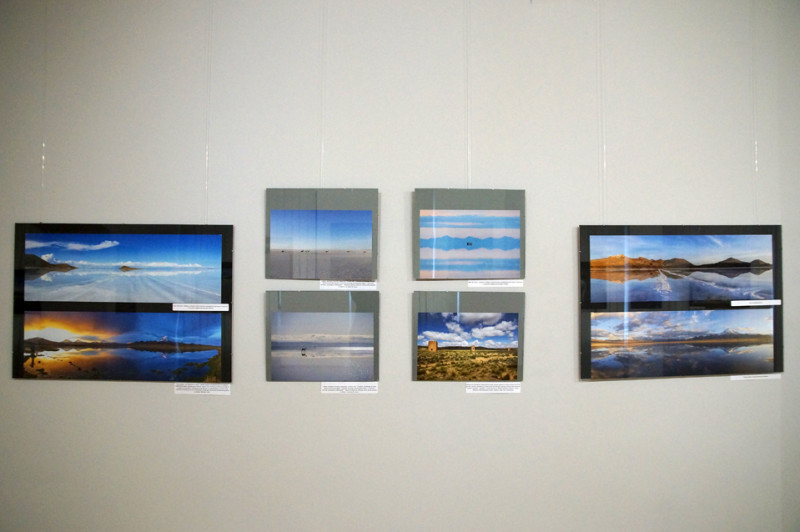 Fragment ekspozycji - osiem fotografii przedstawiających krajobraz Boliwii, jeziora, góry, odbicia nieba w tafli jezior