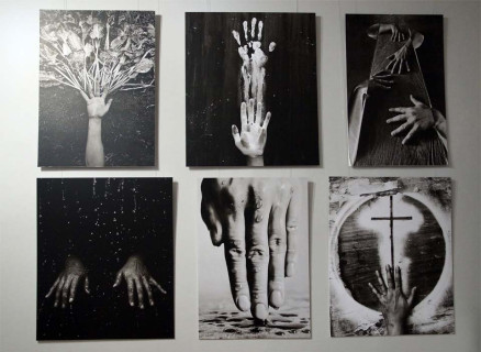 Fragment ekspozycji - na ścianie zawieszony cykl czarno-białych fotografii z motywem dłoni